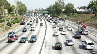 Heavy traffic moves in opposite directions along a four lane freeway in Los Angeles