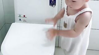 A very cute baby. This kid is washing dishes to his heart's content