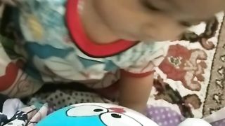 baby looking at Doraemon doll