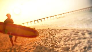 A Surfer Walks Down To The Beach At Sunset