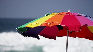 Static Shot Of A Colorful Umbrella With Sea Waves