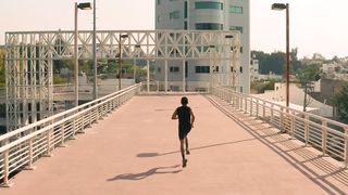 Man jogging on a pedestrian bridge in the city