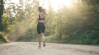 Young woman running thru the forest on a sunny day