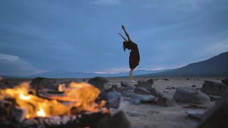 mixkit-deserted-plain-with-a-campfire-and-a-woman-practicing-yoga-32764-medium.