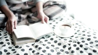 Woman sitting on a polkadot quilt reading a book