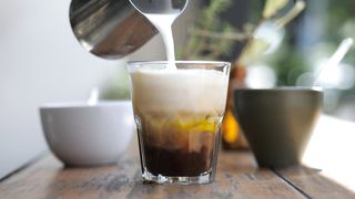 A barista preparing coffee with milk and ice