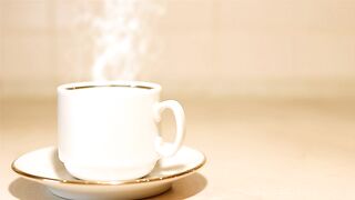Steaming  cup of fresh coffee in a ceramic, gold trimmed mug