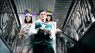Man throwing bills with a couple of female dancers