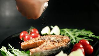 A cooked salmon steak with herbs and vegetables