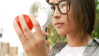 Agronomist checking a tomato with a magnifying glass