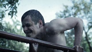 Shirtless man exercises in the rain