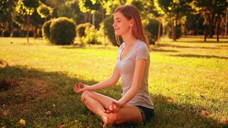 Girl meditating in yoga pose in a park