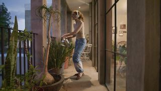 Young woman dancing while watering her plants