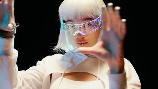A young woman wearing futuristic VR glasses focuses