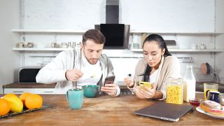 Couple having breakfast cereal and see their cell phones