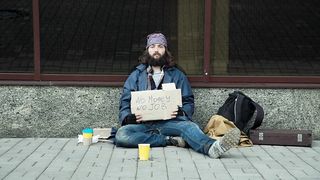 A homeless man begging sitting on the street