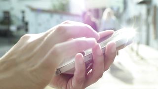 Hands using a mobile phone on the street
