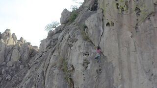 Mountaineer girl climbing a steep rocky mountain