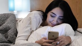 Girl lying down chatting on her cell phone before sleeping