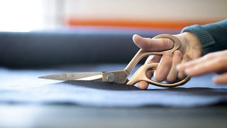 Scissors cutting a blue fabric