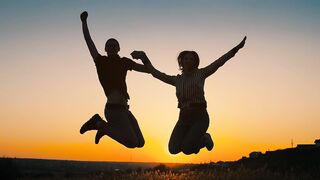Silhouette of a couple jumping in the sunset