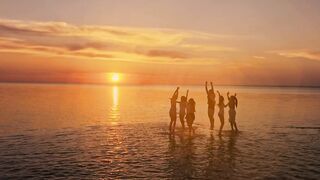 Dreamy sunset view of people jumping on sea surface