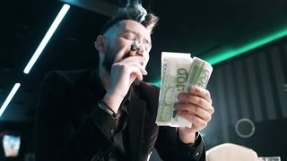Bearded man counting money while he smokes