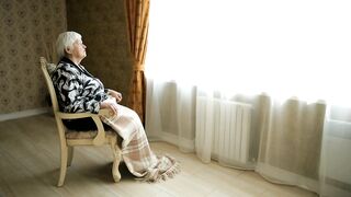 Elderly woman sitting in front of the window