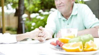 Old couple holding hands at the table