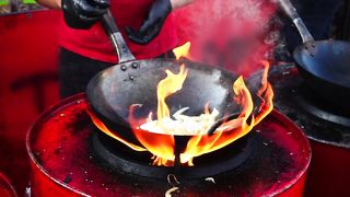 Person cooking in a wok pan with high flame