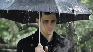 Sad man at a funeral raining with umbrella