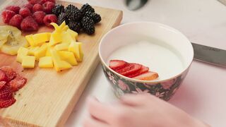 Preparing a bowl with yogurt and fruit