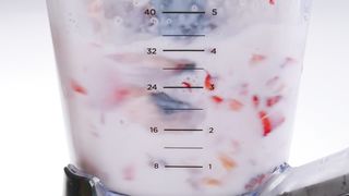 A blender full of fresh fruit and milk starts sppining