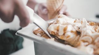 A Person Putting Scoop of Ice Cream in a Cone