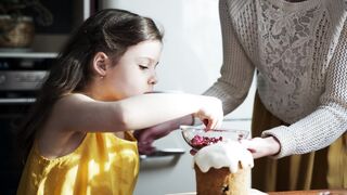 A Girl Is Placing Topping On A Cake