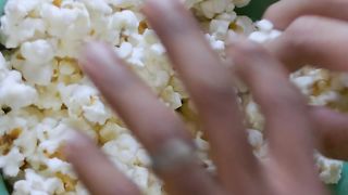 Friends taking popcorn from a bowl
