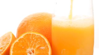 Serving juice in a glass with some oranges on a white background