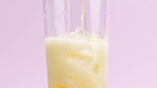 A crystal glass with ice fills up with effervescent orange soda