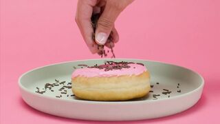 Sprinkling chocolate chips on a donut