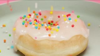 Spreading colorful pieces on a glazed donut