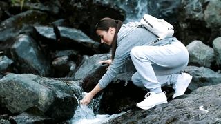Woman drinks water from the waterfall