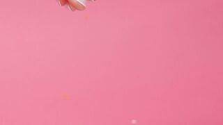 Woman sprinkling colored sprinkles on a donut