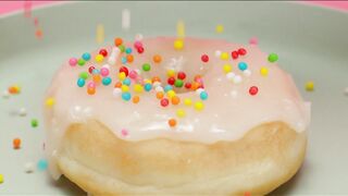 Spreading colorful pieces on a glazed donut