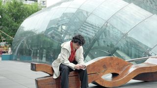 a-young-man-sitting-on-a-wooden-bench-using-his-smartphone