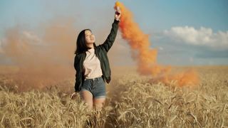 Happy girl jumping with a smoke flare