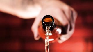Person pouring beer from a glass bottle