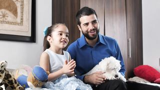 Family Time: Father, Daughter, and Their Little Dog Enjoying TV Together