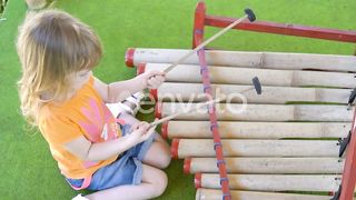 Little Girl Plays with Special Sticks on Traditional Indonesian Instruments