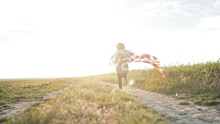 Cute Little Boy American Patriot Kid Running with National Flag on Open Area Countryside Road - USA 4th of July Celebration
