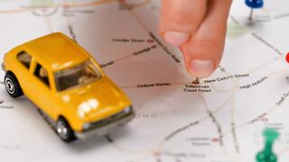 Map of a city with a toy car and pushpins